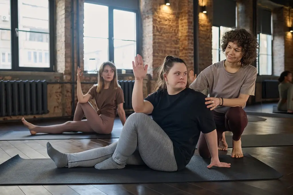 A personal trainer assists a young woman with a stretch during a yoga session, highlighting the tailored support in personal training